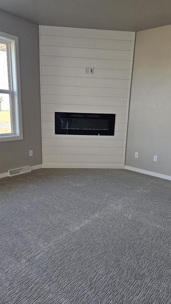 unfurnished living room with carpet flooring and a large fireplace