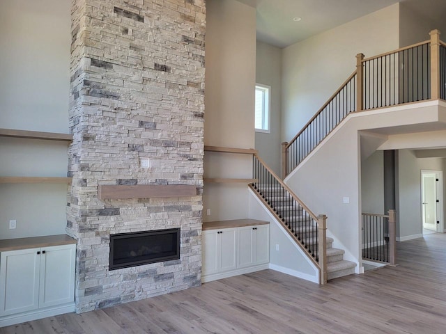 unfurnished living room featuring a fireplace, a high ceiling, and light wood-type flooring