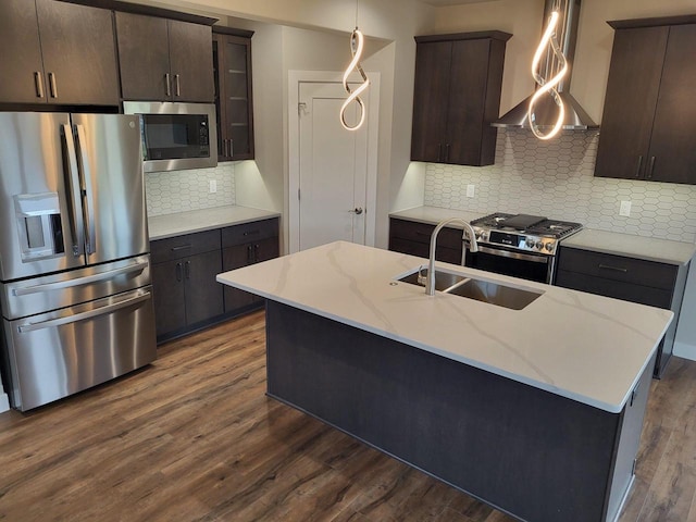 kitchen featuring backsplash, stainless steel appliances, hardwood / wood-style floors, and an island with sink