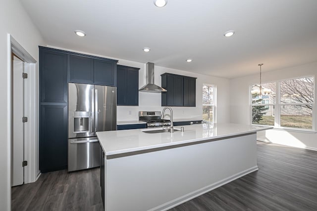 kitchen featuring wall chimney exhaust hood, sink, dark wood-type flooring, stainless steel appliances, and a kitchen island with sink