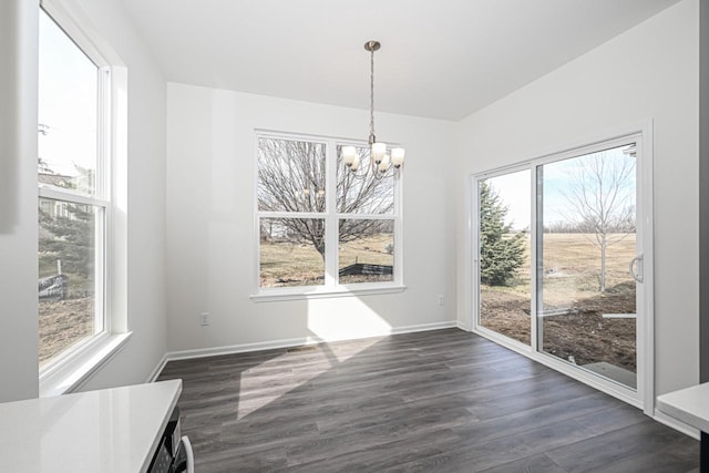 unfurnished dining area featuring a notable chandelier, a healthy amount of sunlight, and dark wood-type flooring