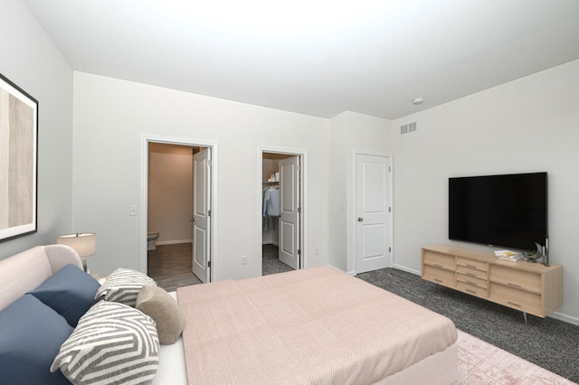 carpeted bedroom with ensuite bath and a spacious closet