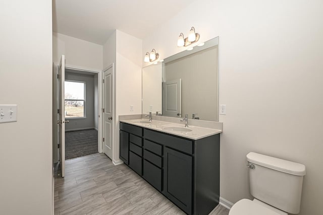 bathroom featuring toilet and double sink vanity