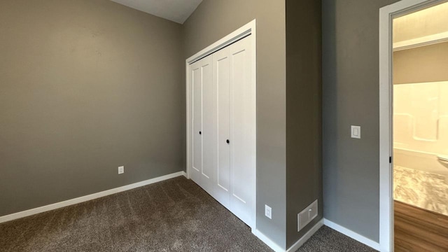 unfurnished bedroom featuring dark carpet and a closet