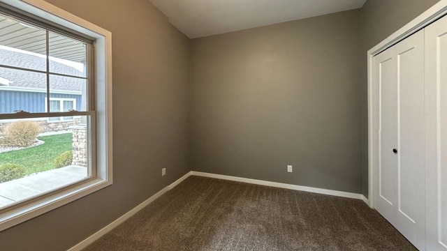 unfurnished bedroom with a closet and dark colored carpet