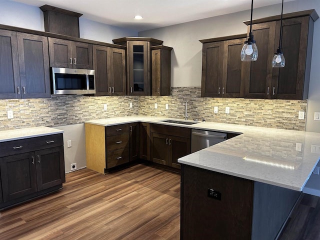 kitchen featuring backsplash, appliances with stainless steel finishes, hardwood / wood-style flooring, pendant lighting, and sink