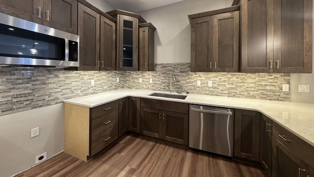 kitchen featuring dark hardwood / wood-style floors, stainless steel appliances, sink, dark brown cabinetry, and tasteful backsplash