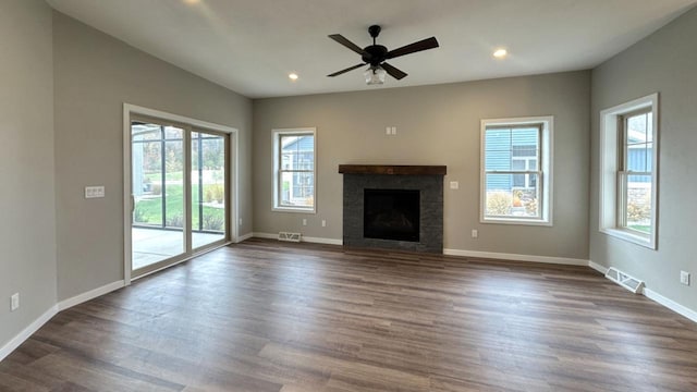 unfurnished living room with a healthy amount of sunlight, dark wood-type flooring, and ceiling fan