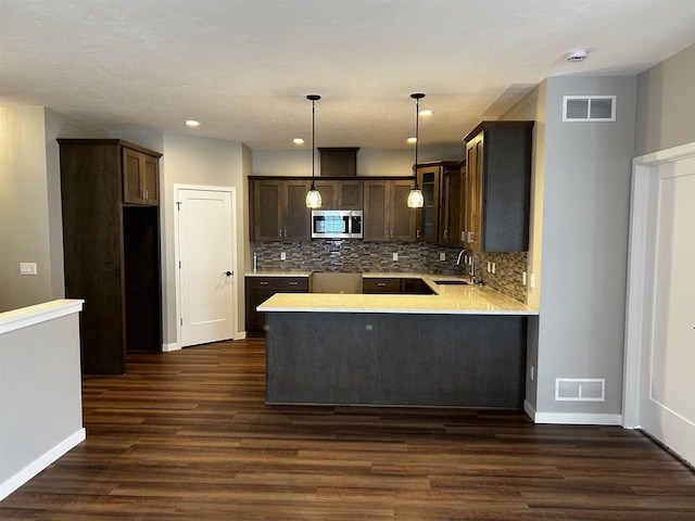 kitchen featuring kitchen peninsula, sink, hanging light fixtures, and dark hardwood / wood-style flooring