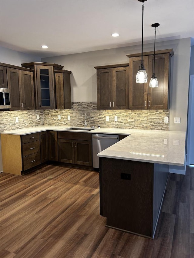 kitchen featuring dark brown cabinetry, decorative light fixtures, stainless steel appliances, and dark hardwood / wood-style flooring