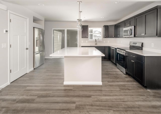 kitchen featuring sink, decorative light fixtures, a kitchen island, stainless steel appliances, and light hardwood / wood-style floors