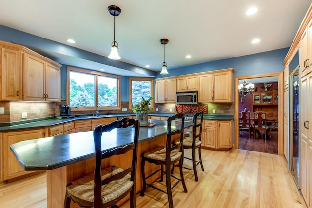 3310 Saracen Way, Verona, WI 53593 - kitchen with stainless steel microwave, dark countertops, a kitchen breakfast bar, recessed lighting, and backsplash