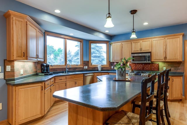 3310 Saracen Way, Verona, WI 53593 - kitchen featuring appliances with stainless steel finishes, dark countertops, a kitchen bar, light wood-style flooring, and a kitchen island