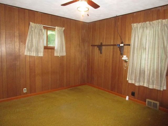 unfurnished room with wooden walls, ceiling fan, and carpet floors