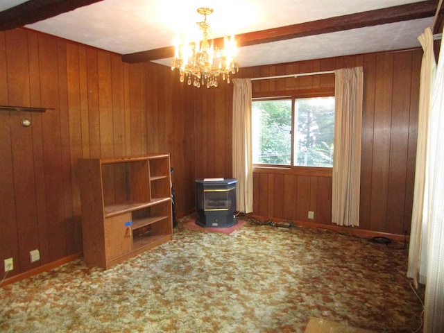 unfurnished room with carpet floors, wooden walls, beam ceiling, and a wood stove