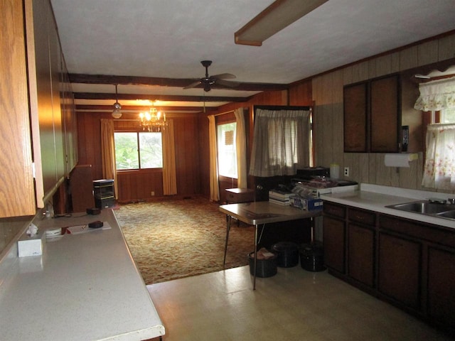 kitchen featuring sink, ceiling fan with notable chandelier, wooden walls, dark brown cabinetry, and carpet