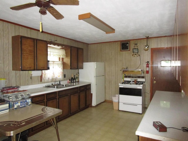 kitchen featuring wood walls, white appliances, light tile floors, sink, and ceiling fan