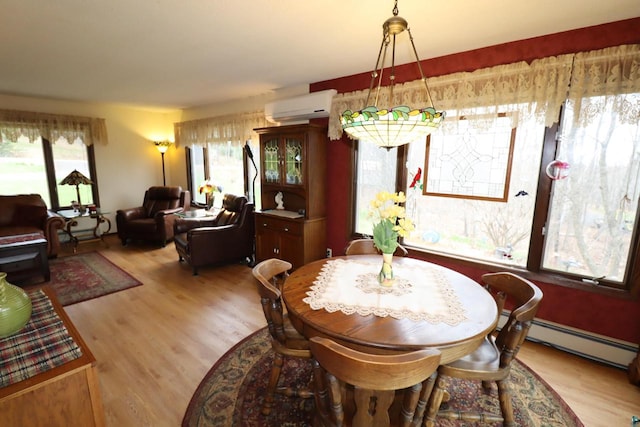 dining room featuring light hardwood / wood-style floors, baseboard heating, and a wall unit AC