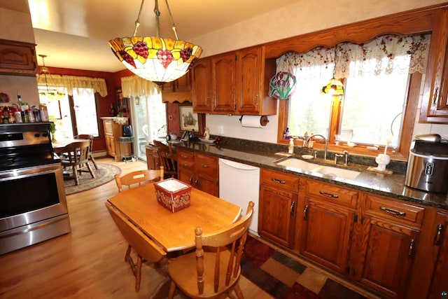 kitchen with sink, dishwasher, hanging light fixtures, stainless steel range oven, and light wood-type flooring