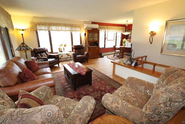 living room featuring baseboard heating, a wall mounted AC, and light hardwood / wood-style flooring