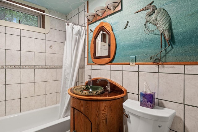 full bathroom with tile walls, shower / bath combo with shower curtain, toilet, and vanity