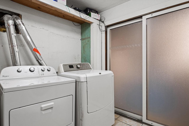 clothes washing area with light tile floors and washing machine and clothes dryer