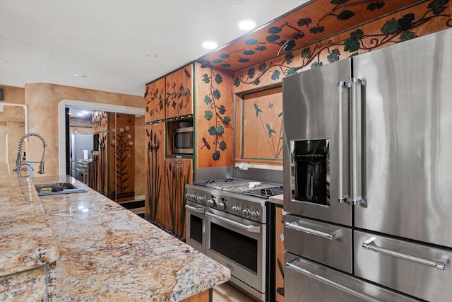 kitchen with light stone counters, sink, and high quality appliances