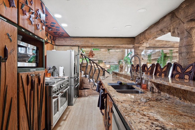 kitchen featuring light hardwood / wood-style floors, appliances with stainless steel finishes, sink, and light stone countertops