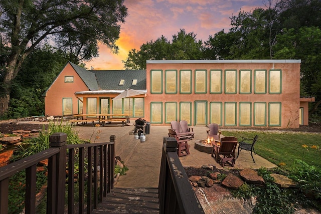 back house at dusk featuring a patio and an outdoor fire pit