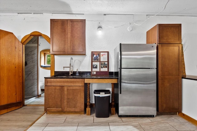 kitchen with sink, stainless steel refrigerator, and light hardwood / wood-style flooring