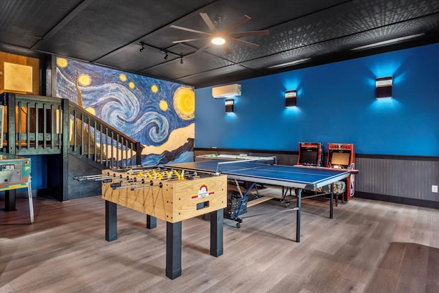 game room with wood-type flooring, ceiling fan, and a wall mounted AC