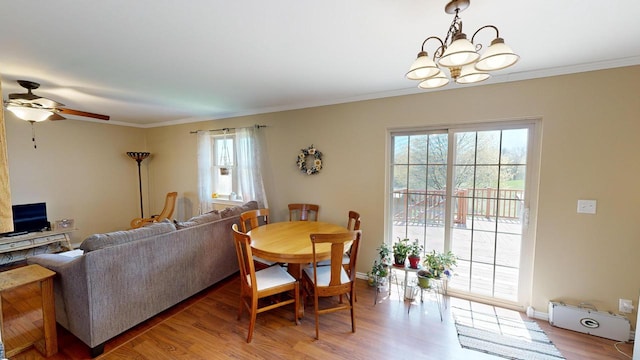 dining area with ceiling fan with notable chandelier, crown molding, and hardwood / wood-style flooring