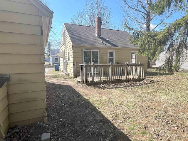 back of property featuring roof with shingles, a chimney, and a wooden deck