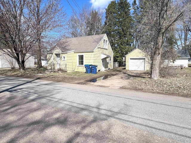 view of side of home featuring aphalt driveway, an outdoor structure, a detached garage, and a shingled roof