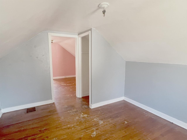 bonus room with baseboards, visible vents, vaulted ceiling, and wood finished floors