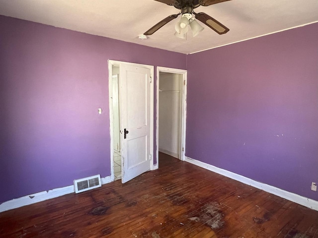 unfurnished bedroom featuring a ceiling fan, baseboards, visible vents, and wood finished floors