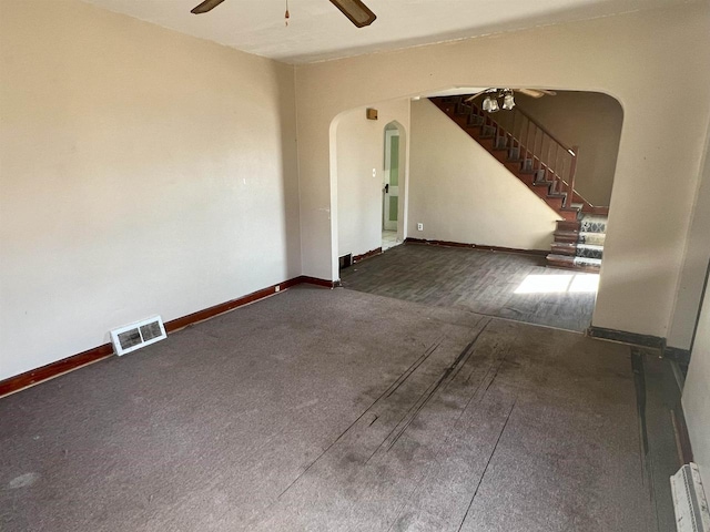 empty room with arched walkways, visible vents, ceiling fan, baseboards, and stairs