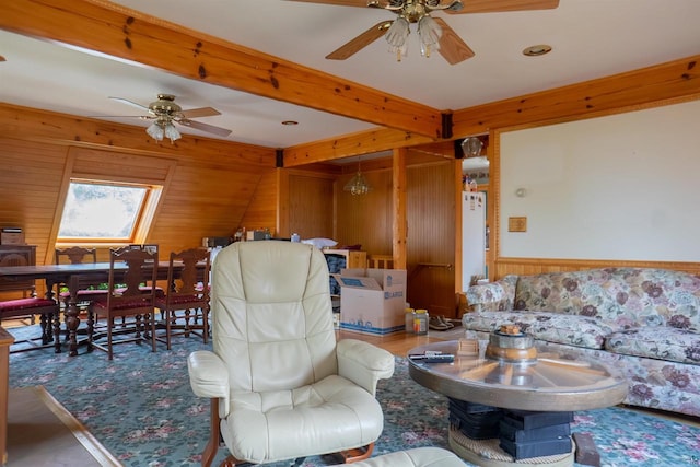 living room with a skylight, ceiling fan, and wooden walls