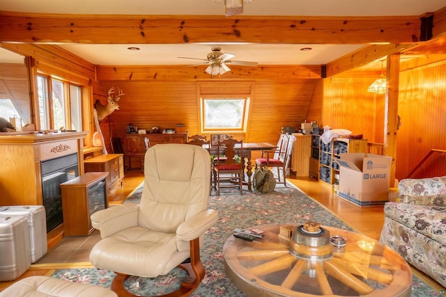 living room with beamed ceiling, ceiling fan, a healthy amount of sunlight, and wooden walls