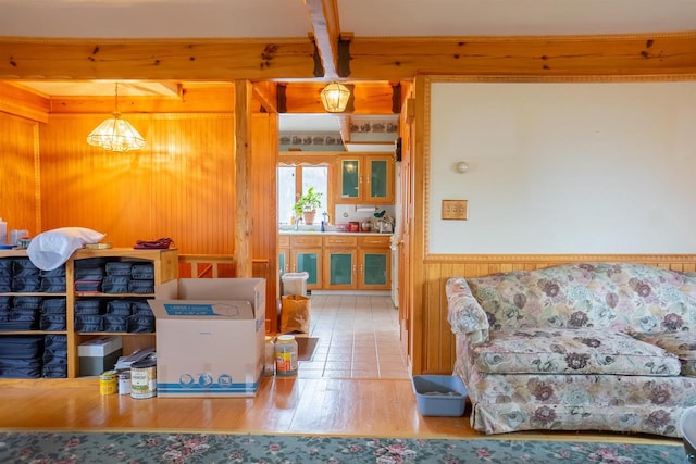 tiled living room featuring wooden walls and beamed ceiling