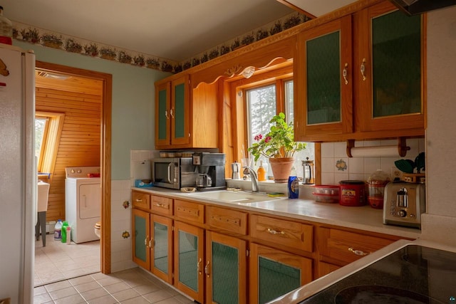 kitchen featuring sink, backsplash, light tile floors, and washer / dryer