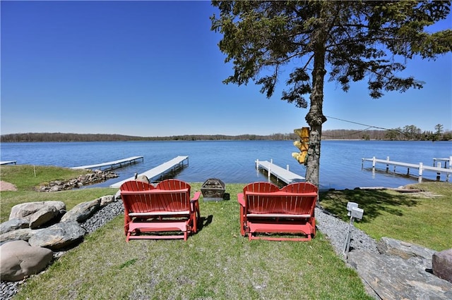 view of dock with a lawn and a water view