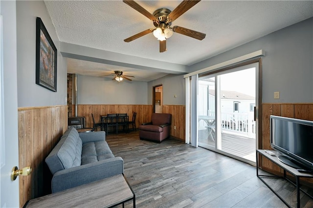 living room featuring wood-type flooring, ceiling fan, and a textured ceiling