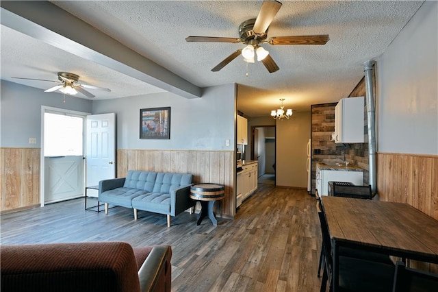 living room with ceiling fan with notable chandelier, wood-type flooring, and a textured ceiling