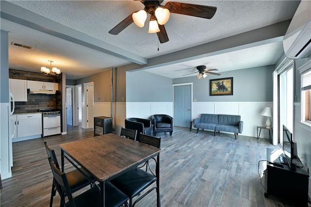 dining space featuring ceiling fan with notable chandelier, a textured ceiling, beam ceiling, a wall unit AC, and dark hardwood / wood-style flooring