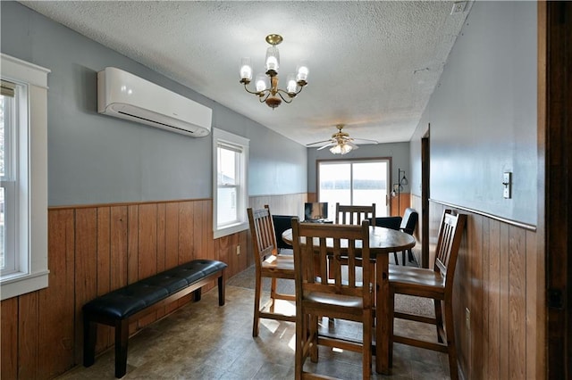 dining area with an AC wall unit, tile floors, ceiling fan with notable chandelier, and a textured ceiling