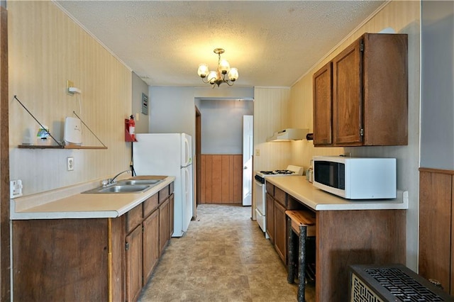 kitchen with white appliances, an inviting chandelier, light tile floors, sink, and a textured ceiling