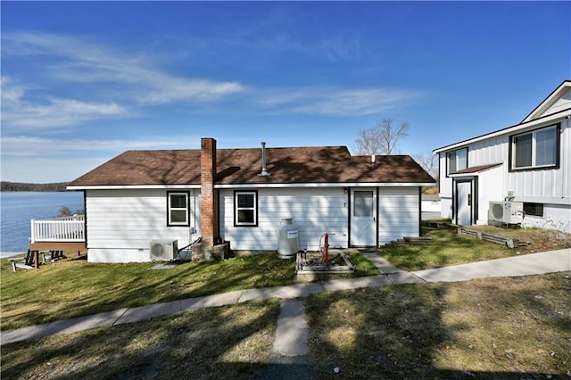 back of property with a water view and a lawn