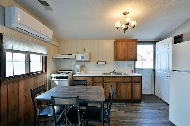 kitchen featuring sink, white appliances, a wall mounted AC, dark hardwood / wood-style flooring, and a chandelier