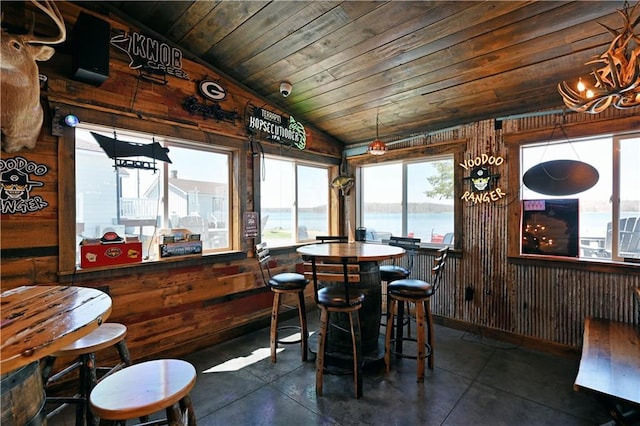 dining room featuring wood ceiling, a water view, vaulted ceiling, and dark tile flooring